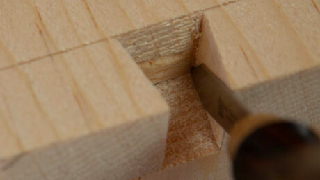 A closeup image of Megan Fitzpatrick carving a dovetail into wood