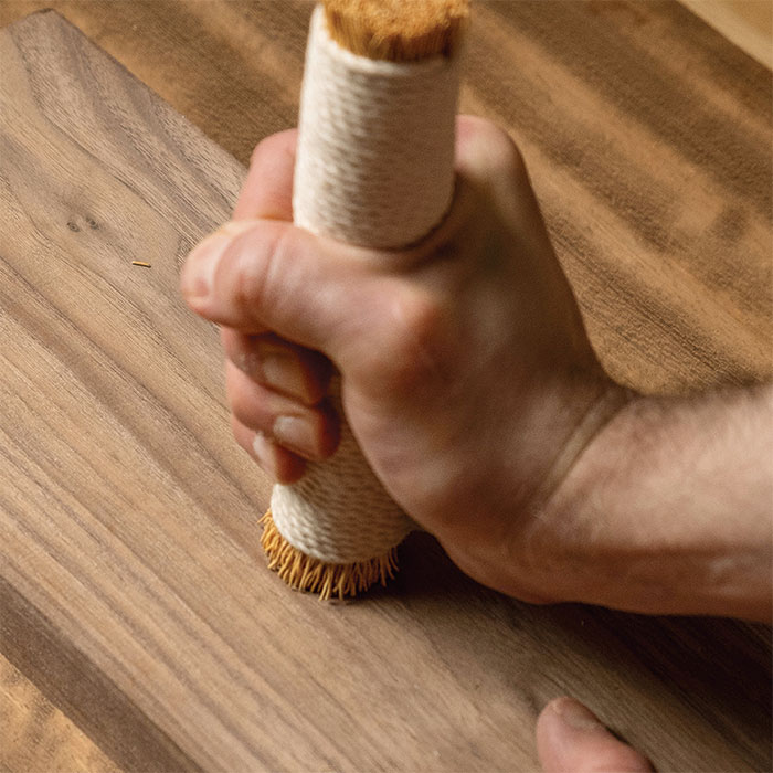 Holding the brush upright with one end firmly flat on the wood surface